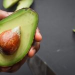 hand holding sliced open avocado
