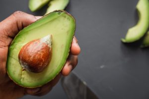 hand holding sliced open avocado